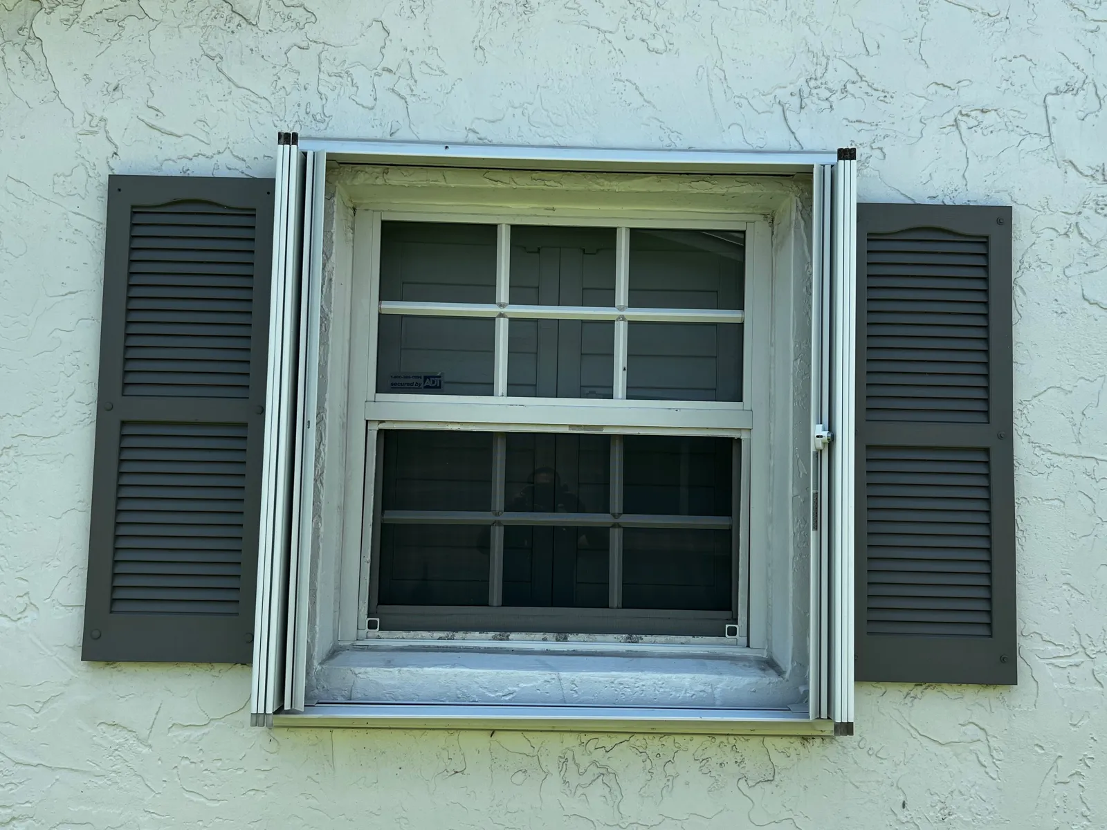 Accordion hurricane shutters beside a window
